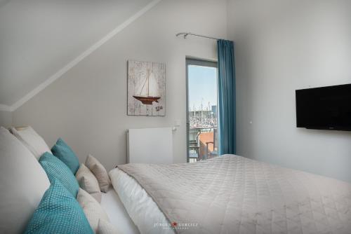 a white bedroom with a bed and a tv at Ostsee - Appartement Nr 20 "Oberdeck" im Strand Resort in Heiligenhafen