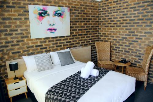 a bedroom with a bed and a brick wall at Squatters Homestead Motel in Casino