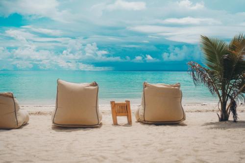 three pillows and a chair on a beach at Amihan Beach Cabanas in Bantayan Island