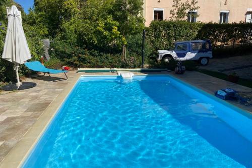 a blue swimming pool with a chair and an umbrella at Elegant House With Terrace Garden And Pool in Sanary-sur-Mer