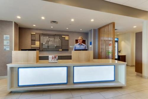 a man standing behind a counter in a lobby at Holiday Inn Express - Wilmington - Porters Neck by IHG in Wilmington