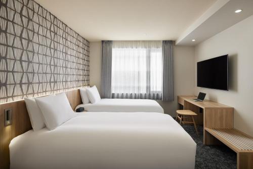 a hotel room with two beds and a television at Oakwood Hotel Oike Kyoto in Kyoto