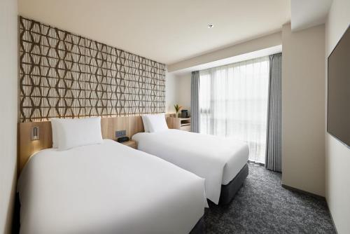 a hotel room with two beds and a window at Oakwood Hotel Oike Kyoto in Kyoto