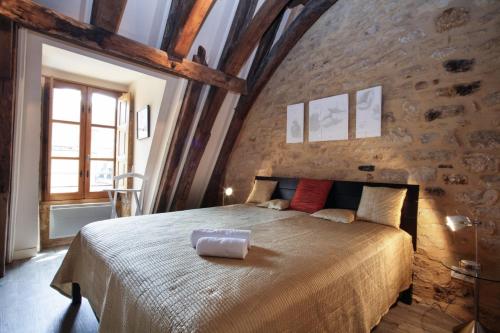 um quarto com uma cama grande numa parede de tijolos em Le Grenier du Chapitre em Sarlat-la-Canéda