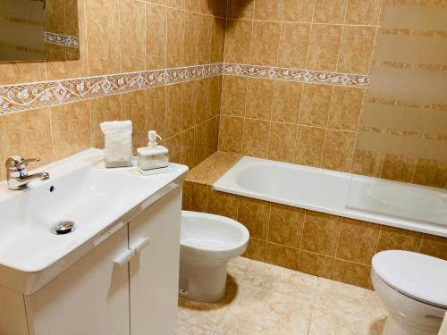 a bathroom with a toilet and a sink and a tub at Apartamentos Las Brisas, Ojedo-Potes in Ojedo