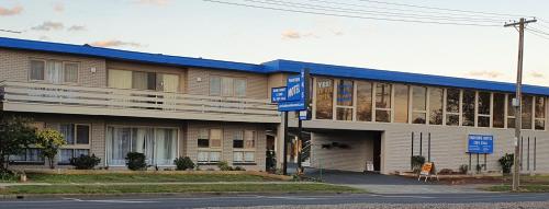 a large building with a blue roof on a street at Morwell Parkside Motel in Morwell