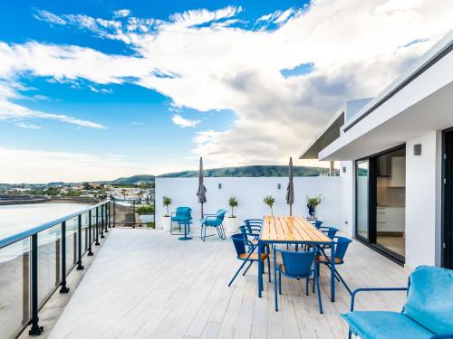 a deck with blue chairs and a table on a balcony at Facing Bay Hostel in Praia da Vitória
