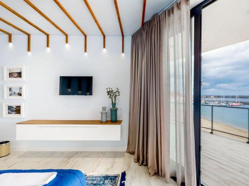 a living room with a tv and a large window at Facing Bay Hostel in Praia da Vitória