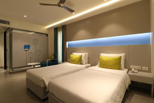 2 camas en una habitación de hotel con almohadas amarillas en ZIBE Salem By GRT Hotels, en Salem