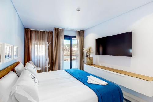 a bedroom with a large bed with a tv on the wall at Facing Bay Hostel in Praia da Vitória
