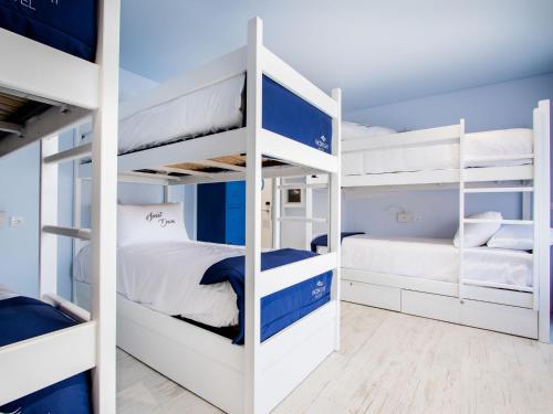 a bedroom with white bunk beds with blue accents at Facing Bay Hostel in Praia da Vitória