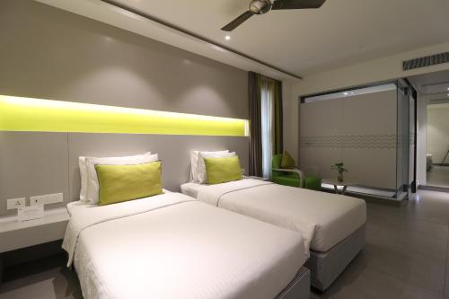 two beds with green pillows in a hotel room at ZIBE Salem By GRT Hotels in Salem