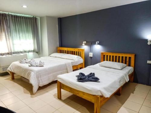 two beds in a hotel room with towels on them at The Moon House in Chiang Mai