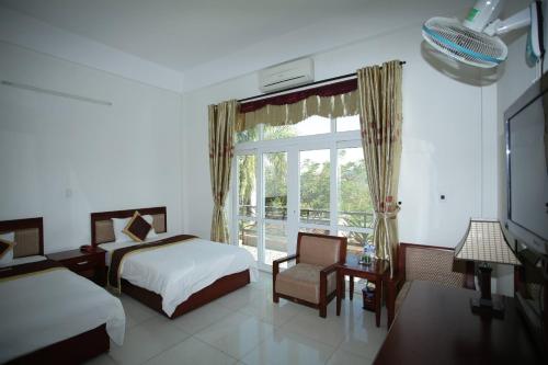 a bedroom with two beds and a large window at Đào Hùng Hotel in Lao Bao