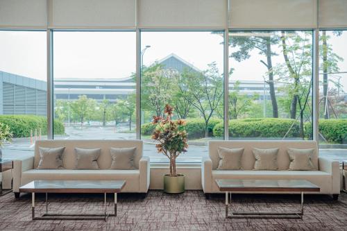 due divani bianchi in una grande stanza con finestre di LOTTE City Hotel Gimpo Airport a Seul