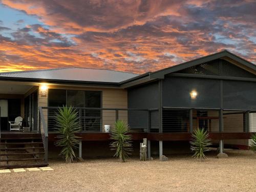 a house with palm trees in front of a sunset at 12 Lady Bay in Normanville