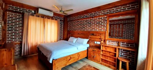 a bedroom with a bed and a brick wall at Kiwi Backpackers Hostel Pokhara in Pokhara