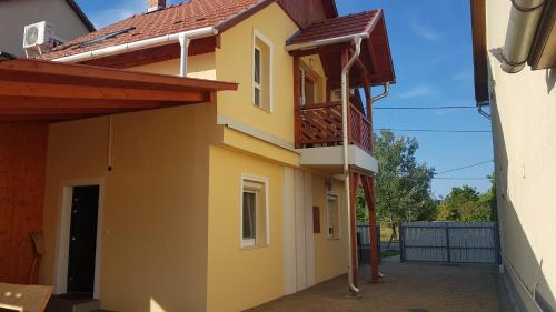 żółty dom z balkonem i ogrodzeniem w obiekcie Kamilla Vendégház w mieście Sárospatak