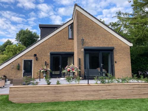 a brick house with flowers in the front yard at Paauwze in Rijnsburg