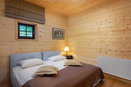 1 dormitorio con 1 cama en una pared de madera en Fenomen Plitvice Gornja Jezera, en Plitvica Selo