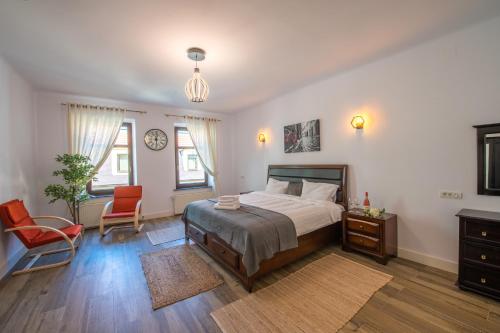 een slaapkamer met een bed en een stoel en een klok bij Old Town Suites Brașov in Braşov