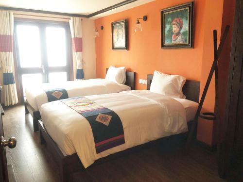 two beds in a hotel room with orange walls at Cat Cat Galerie d’Art in Sa Pa