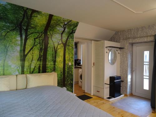 a bedroom with a bed with a forest mural on the wall at Kommod Stuv in Langstedt