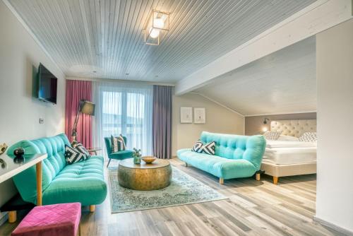 a living room with blue couches and a bed at Hotel Eden Park in Velden am Wörthersee