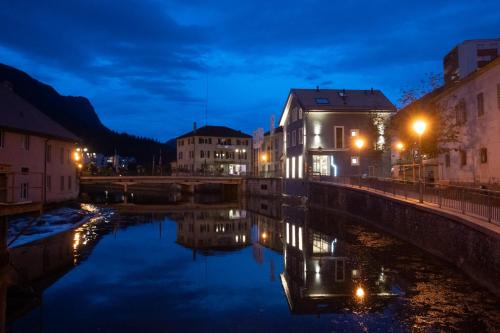 a bridge over a river in a city at night at Hotel de la Concorde - Self Check-in in Vallorbe