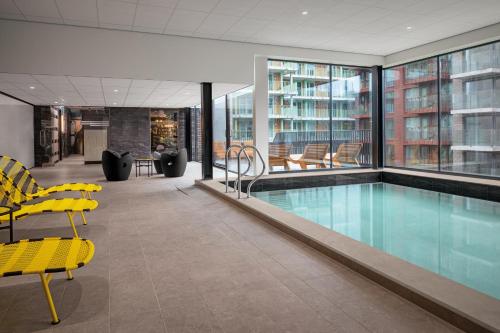 uma piscina num edifício com cadeiras amarelas em Inntel Hotels Amsterdam Landmark em Amesterdão