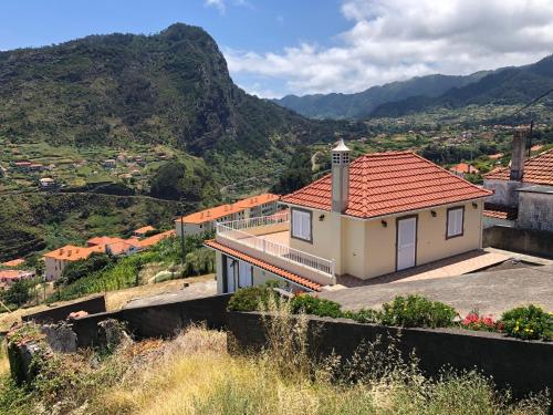 a house on a hill with mountains in the background at Panoramic Ocean View House in Faial