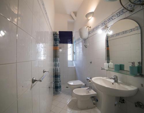 a bathroom with a sink and a toilet and a mirror at La Casetta di Sotto in Forio d'Ischia