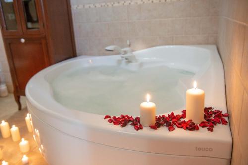 una vasca da bagno con due candele e fiori rossi di Tenuta Ulivi a Putignano