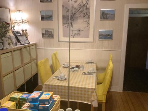 a table with yellow chairs and a table with food on it at Nethermains House in Kilwinning