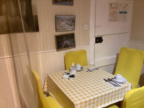 a table with yellow chairs and a table with a table cloth at Nethermains House in Kilwinning