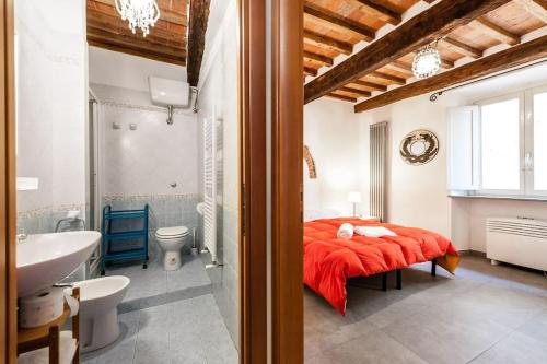 a bedroom with a red bed and a bathroom at B&B Le Donzelle - HiTuscany in Pisa