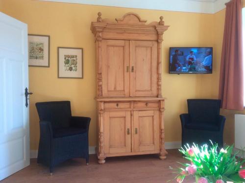 une grande armoire en bois dans une pièce avec deux chaises dans l'établissement Komfort Appartment Hugo, à Eckernförde