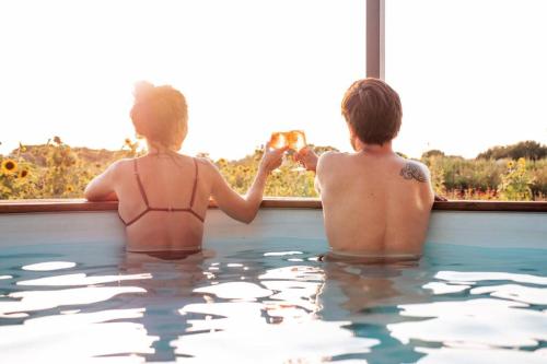 a man and a woman sitting in a swimming pool at myinsolite - Tiny-house, jacuzzi, brasero, piscine in Aigues-Mortes