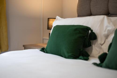 a green pillow sitting on top of a bed at Spacious Home - Parking - Kitchen - Ideal for Work in Swansea