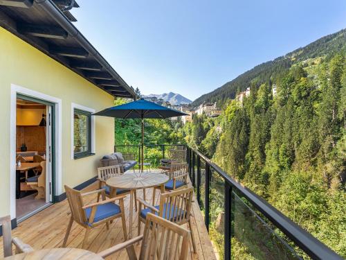 a deck with a table and chairs and an umbrella at Das Schider - Boutique Apart-Hotel in Bad Gastein