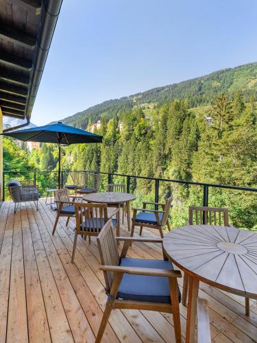 a deck with tables and chairs and a view of the mountains at Das Schider - Boutique Apart-Hotel in Bad Gastein