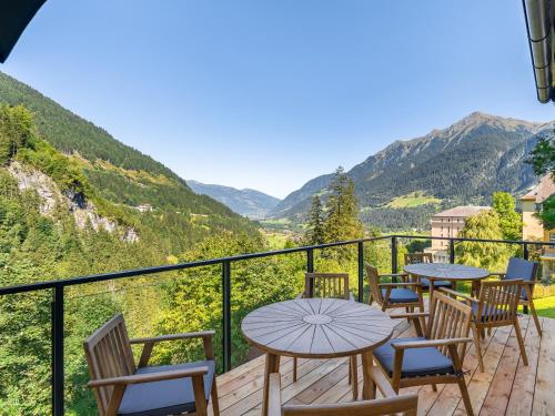 a balcony with tables and chairs and a view of mountains at Das Schider - Boutique Apart-Hotel in Bad Gastein