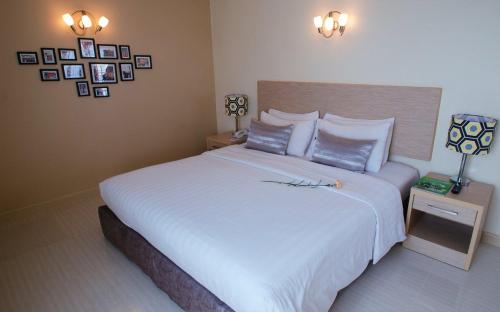 a bedroom with a large white bed with pictures on the wall at Thipurai City Hotel in Hua Hin