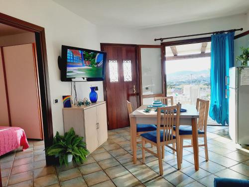 a living room with a table and chairs and a television at Villetta degli Alisei in Santa Teresa Gallura