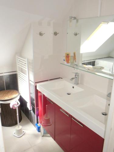 La salle de bains est pourvue d'un lavabo blanc et de placards rouges. dans l'établissement Maison confortable à Ploëzal avec jardin et terrasse, à Ploëzal