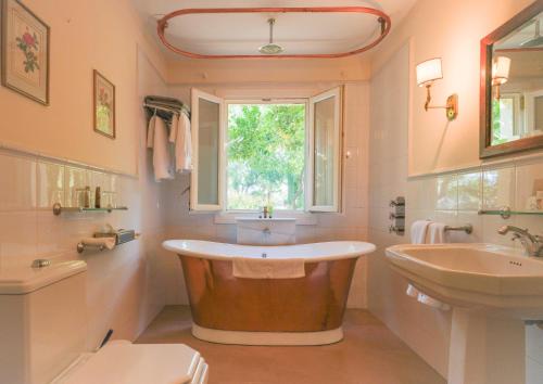 a bathroom with a tub and a sink and a window at Hotel La Fuente de la Higuera in Ronda