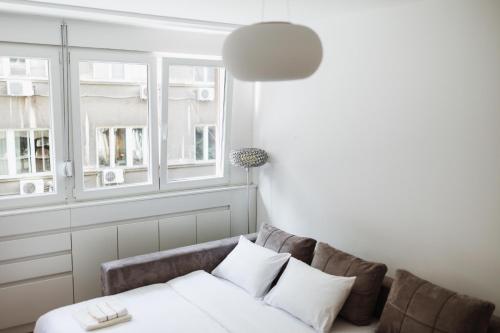 a living room with a couch and two windows at City Center Studio in Belgrade