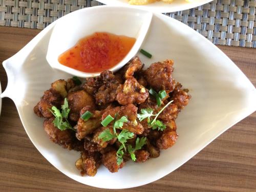 a plate of food with meat and a bowl of sauce at ZIBE Salem By GRT Hotels in Salem