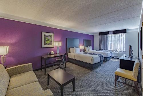 a hotel room with two beds and a couch at Travelodge by Wyndham Houston Cy-Fair in Houston