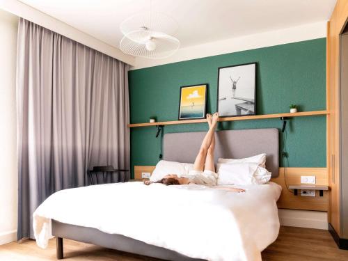 una persona acostada en una cama con sus piernas en el aire en Aparthotel Adagio Annecy Centre, en Annecy